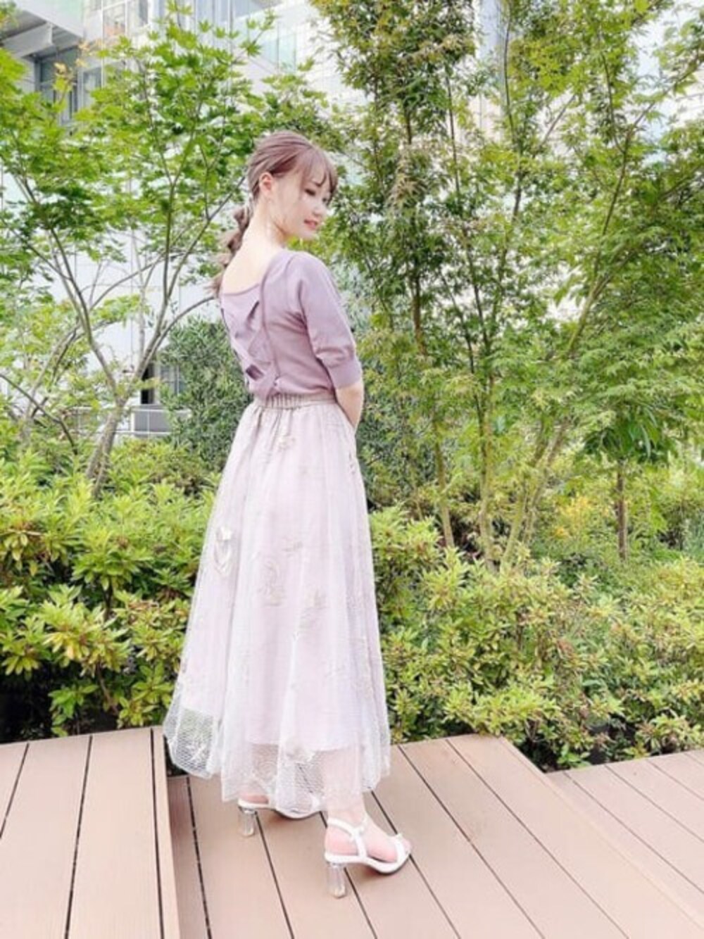 パープル系のニット/セーター、グレー系のスカートを着用したレディースの夏コーディネートの1枚目の写真