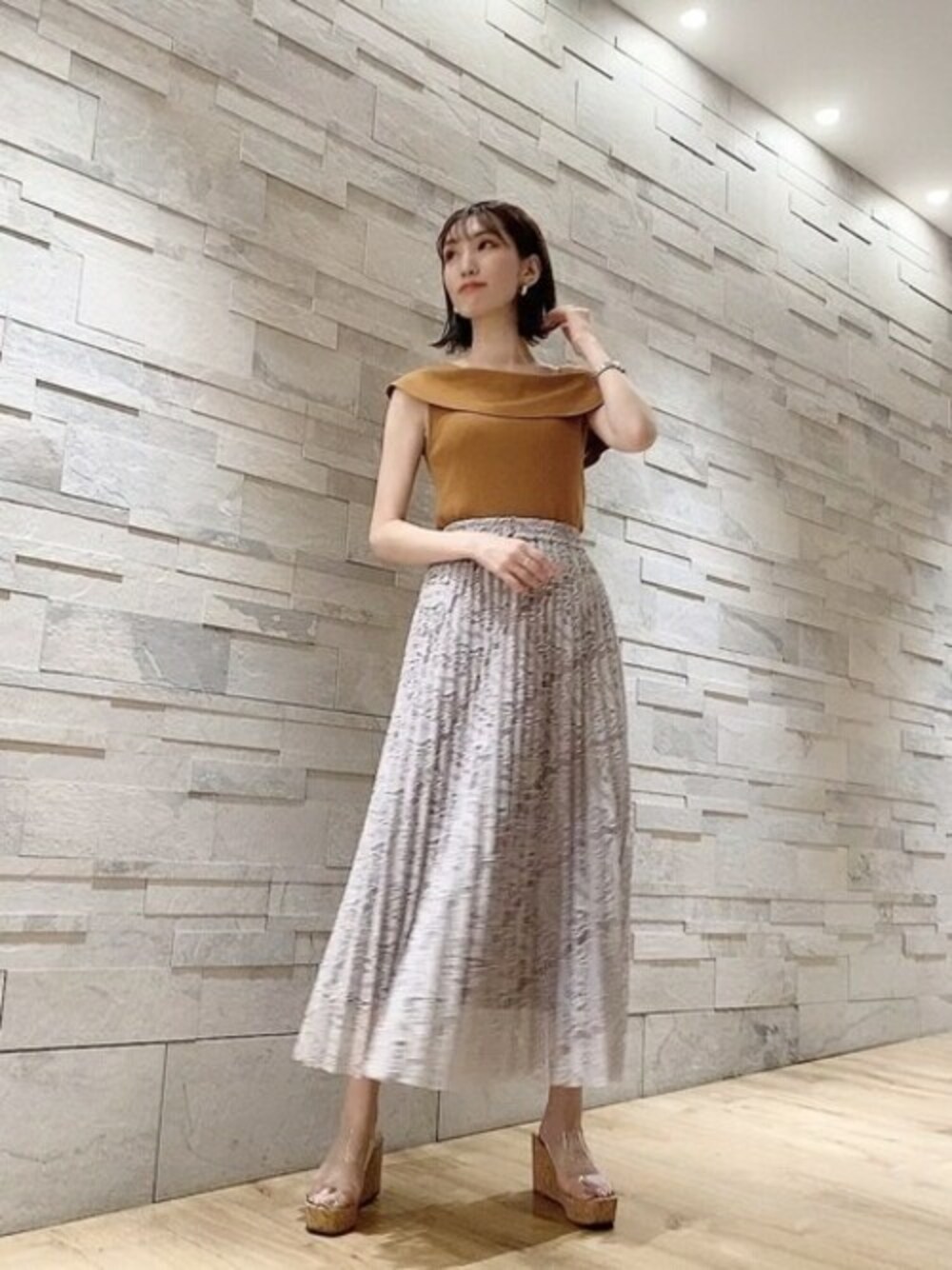 イエロー系のニット/セーター、グレー系のスカートを着用したレディースの夏コーディネートの1枚目の写真