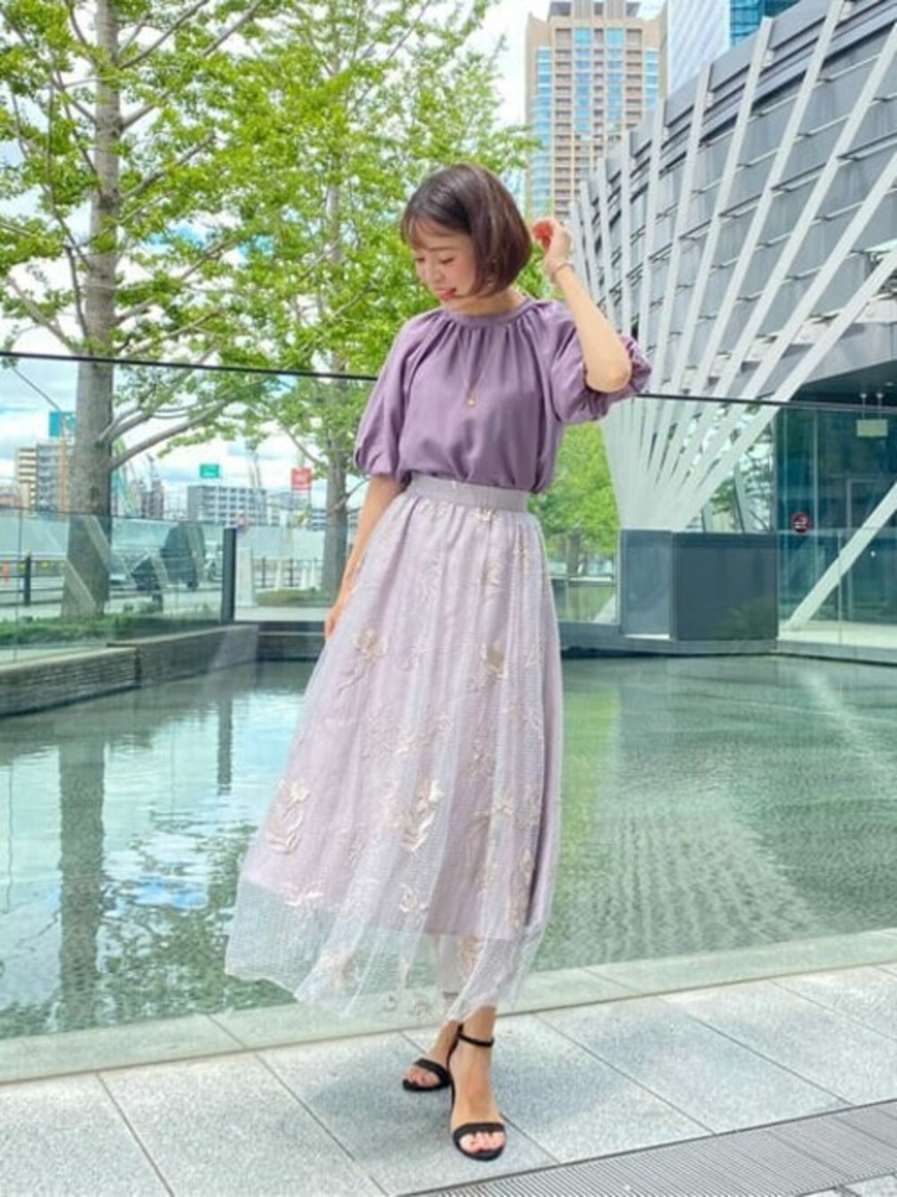 パープル系のシャツ/ブラウス、グレー系のスカートを着用したレディースの夏コーディネートの1枚目の写真