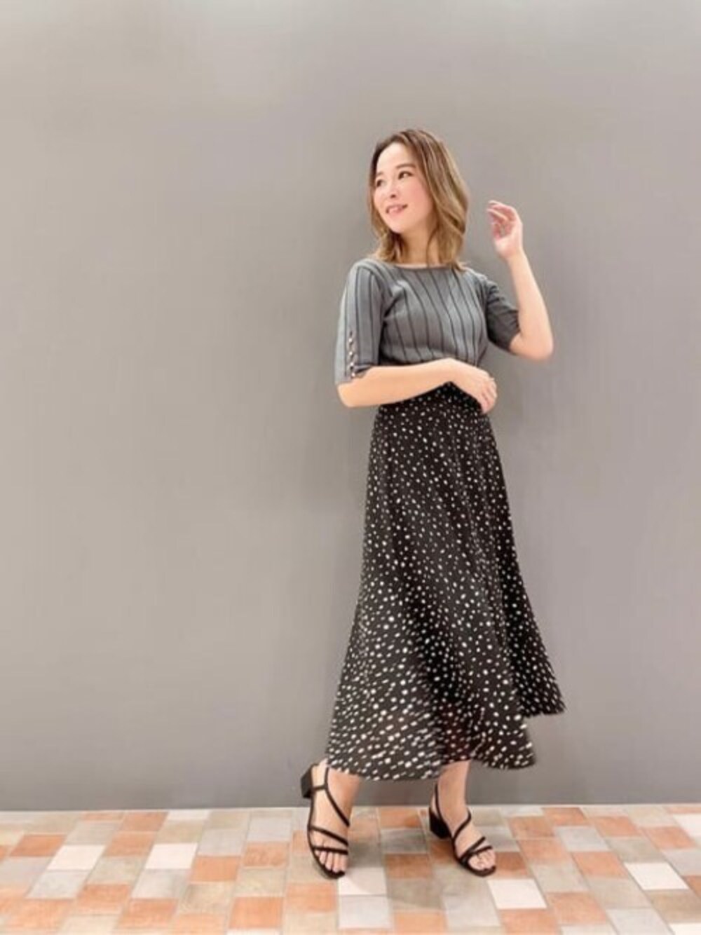 グリーン系のニット/セーター、ブラック系のスカートを着用したレディースの夏コーディネートの1枚目の写真