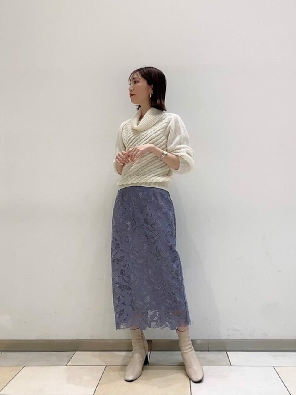 ホワイト系のニット/セーター、ブルー系のスカートを着用したレディースの冬コーディネートの1枚目の写真