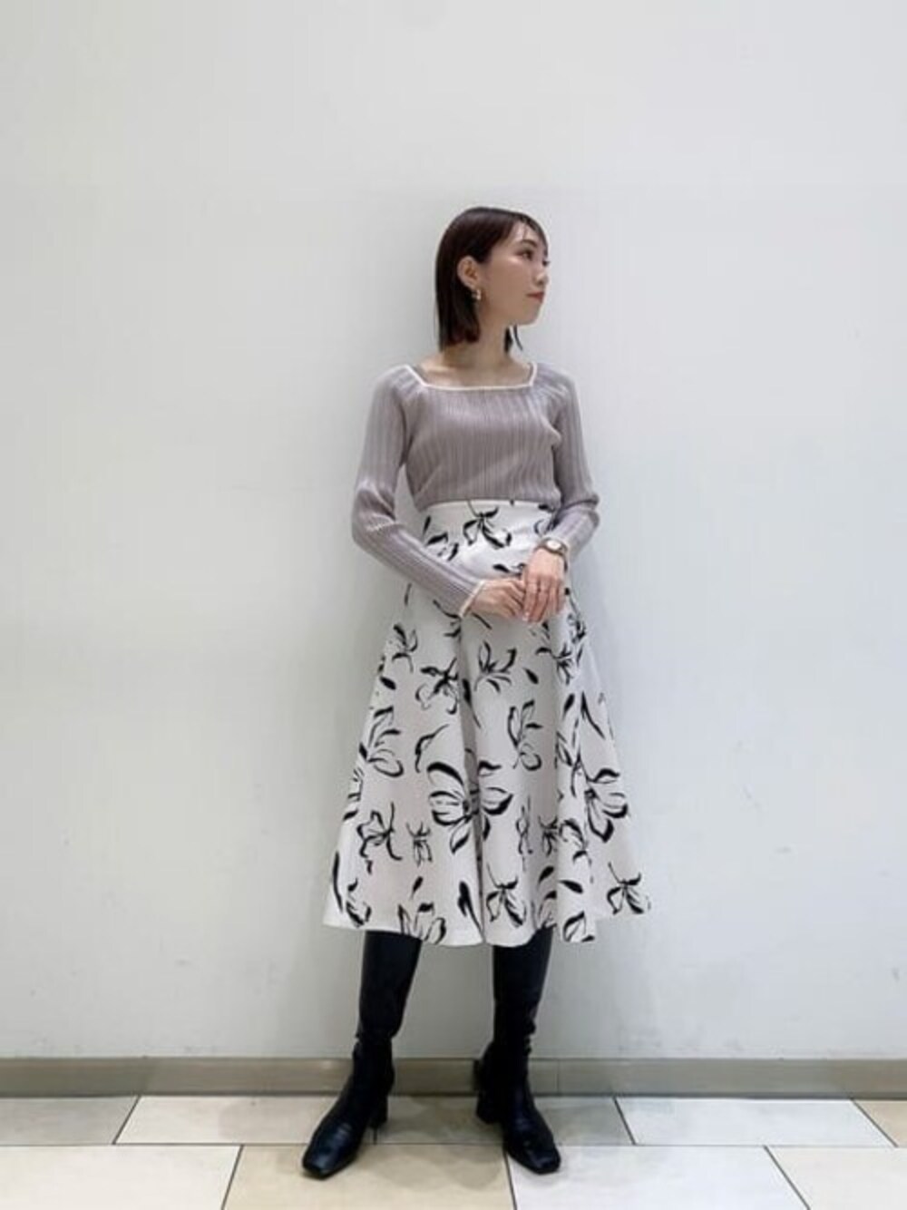 グレー系のニット/セーター、ホワイト系のスカートを着用したレディースの冬コーディネートの1枚目の写真