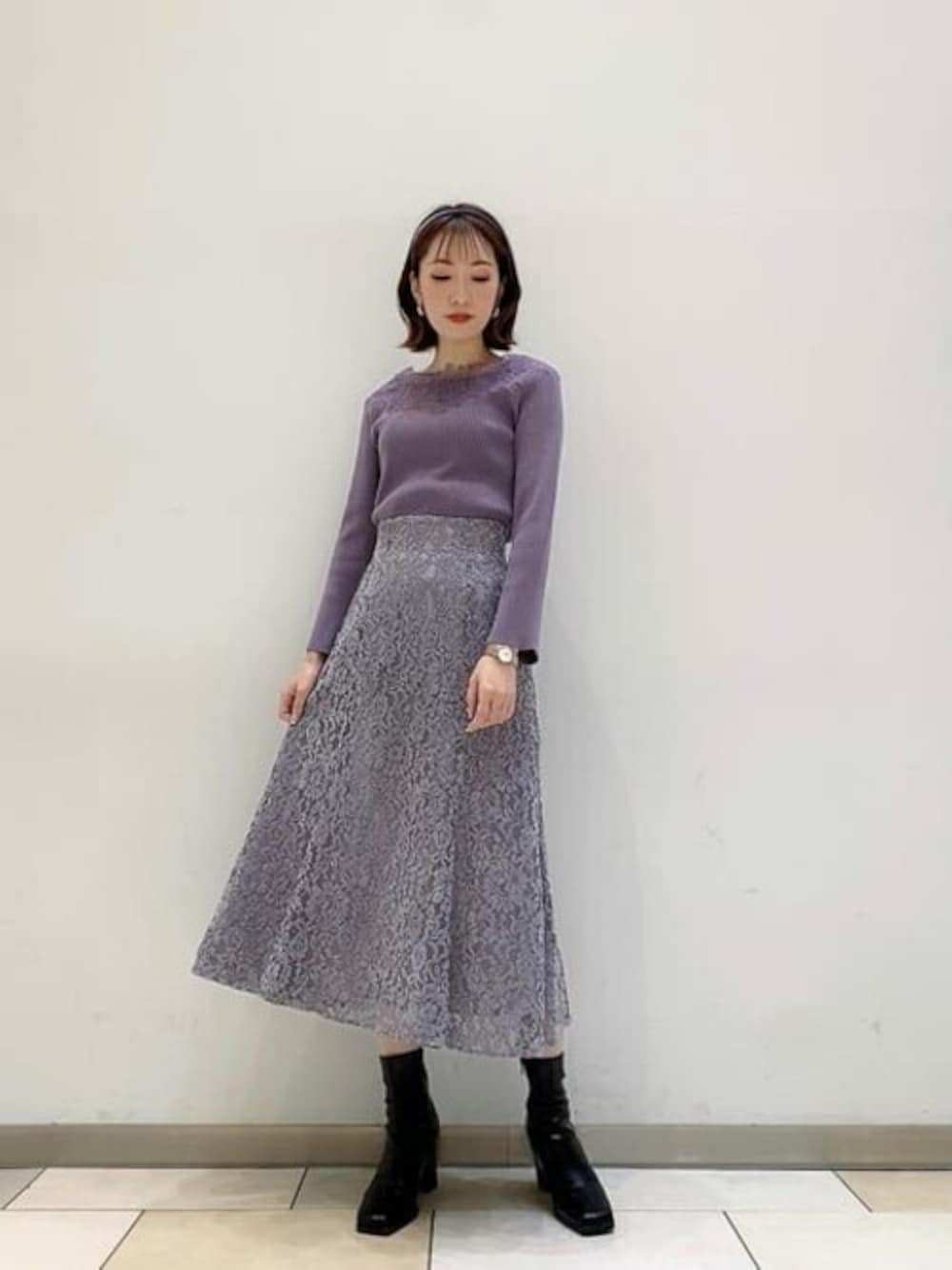 パープル系のニット/セーター、グレー系のスカートを着用したレディースの冬コーディネートの1枚目の写真