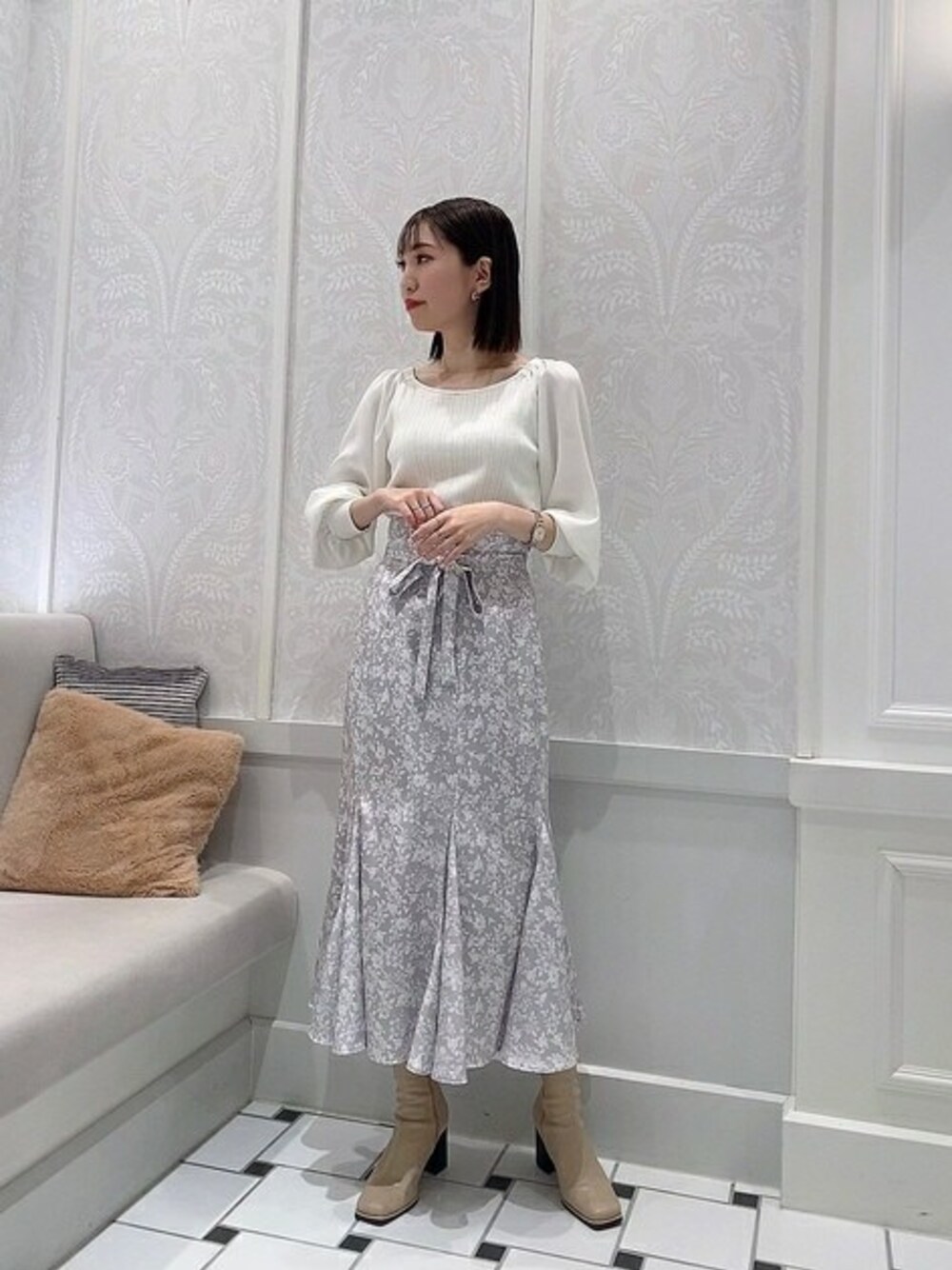 ホワイト系のニット/セーター、グレー系のスカートを着用したレディースの冬コーディネートの1枚目の写真