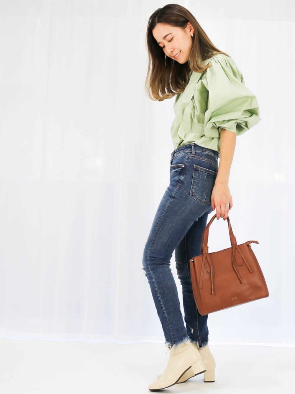 グリーン系のワンピース、ブラウン系のバッグを着用したレディースの春コーディネートの1枚目の写真