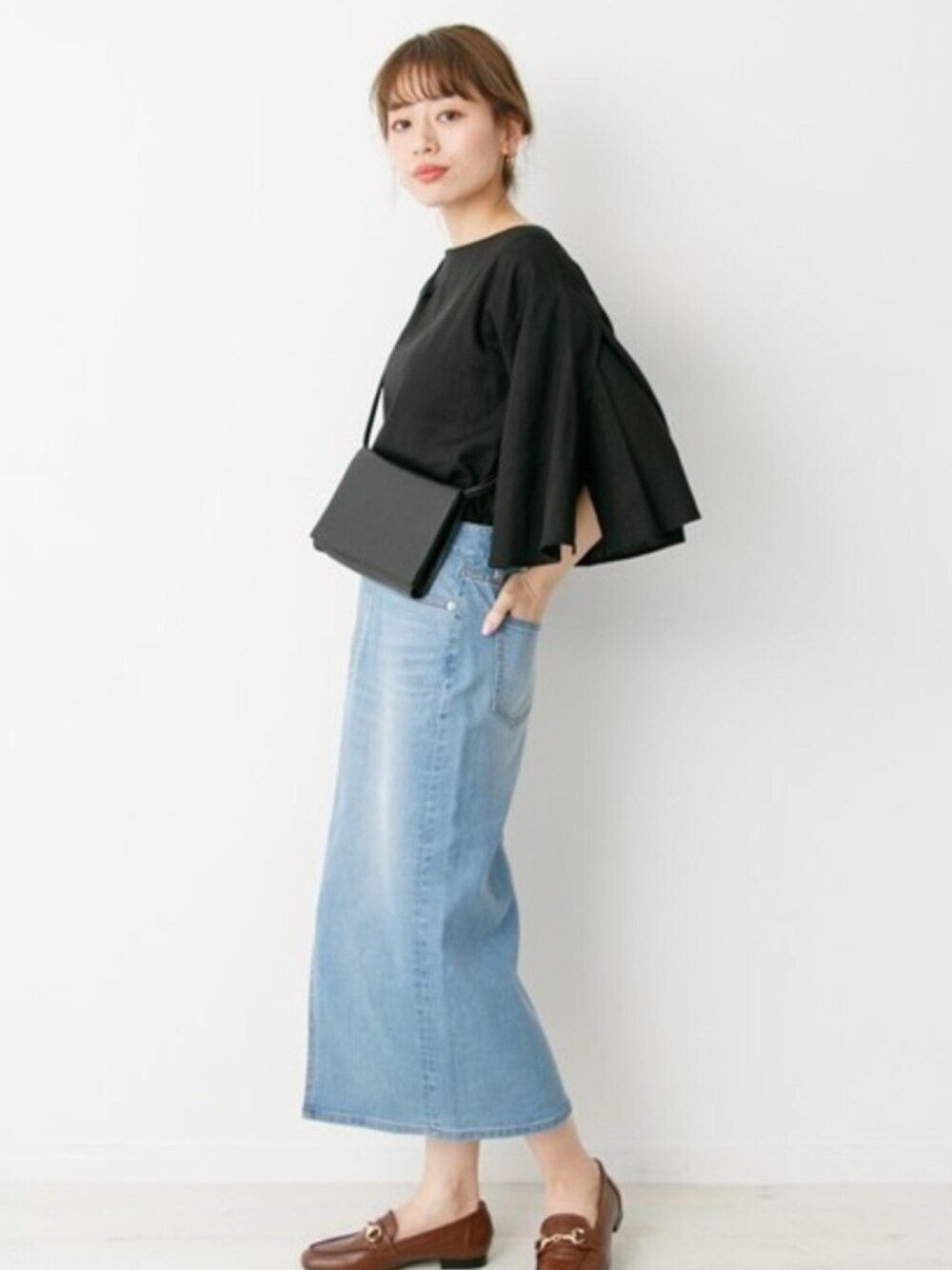 ブルー系のデニムスカート、ブラック系のシャツ/ブラウス、ブラック系のショルダーバッグを着用したレディースの春コーディネートの1枚目の写真