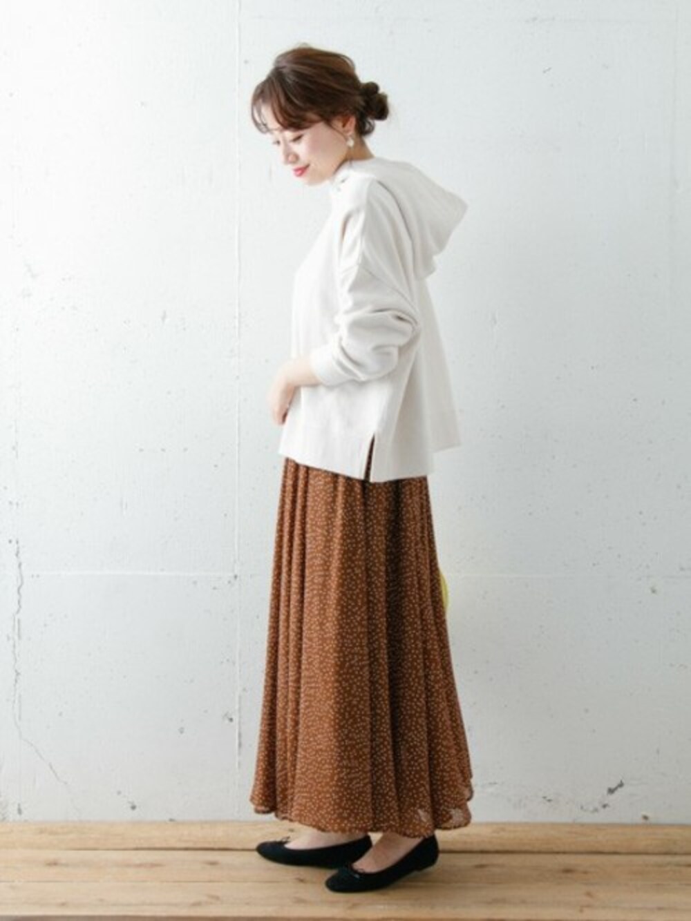 ホワイト系のパーカー、ブラック系のスカートを着用したレディースの冬コーディネートの1枚目の写真