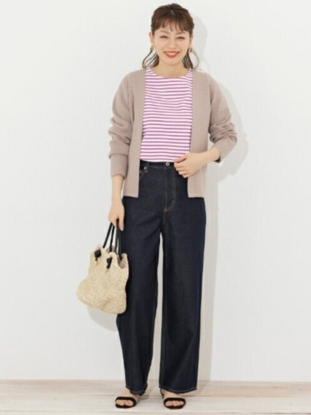 ピンク系のカーディガン/ボレロ、ブルー系のデニムパンツ、ベージュ系のハンドバッグを着用したレディースの冬コーディネートの1枚目の写真