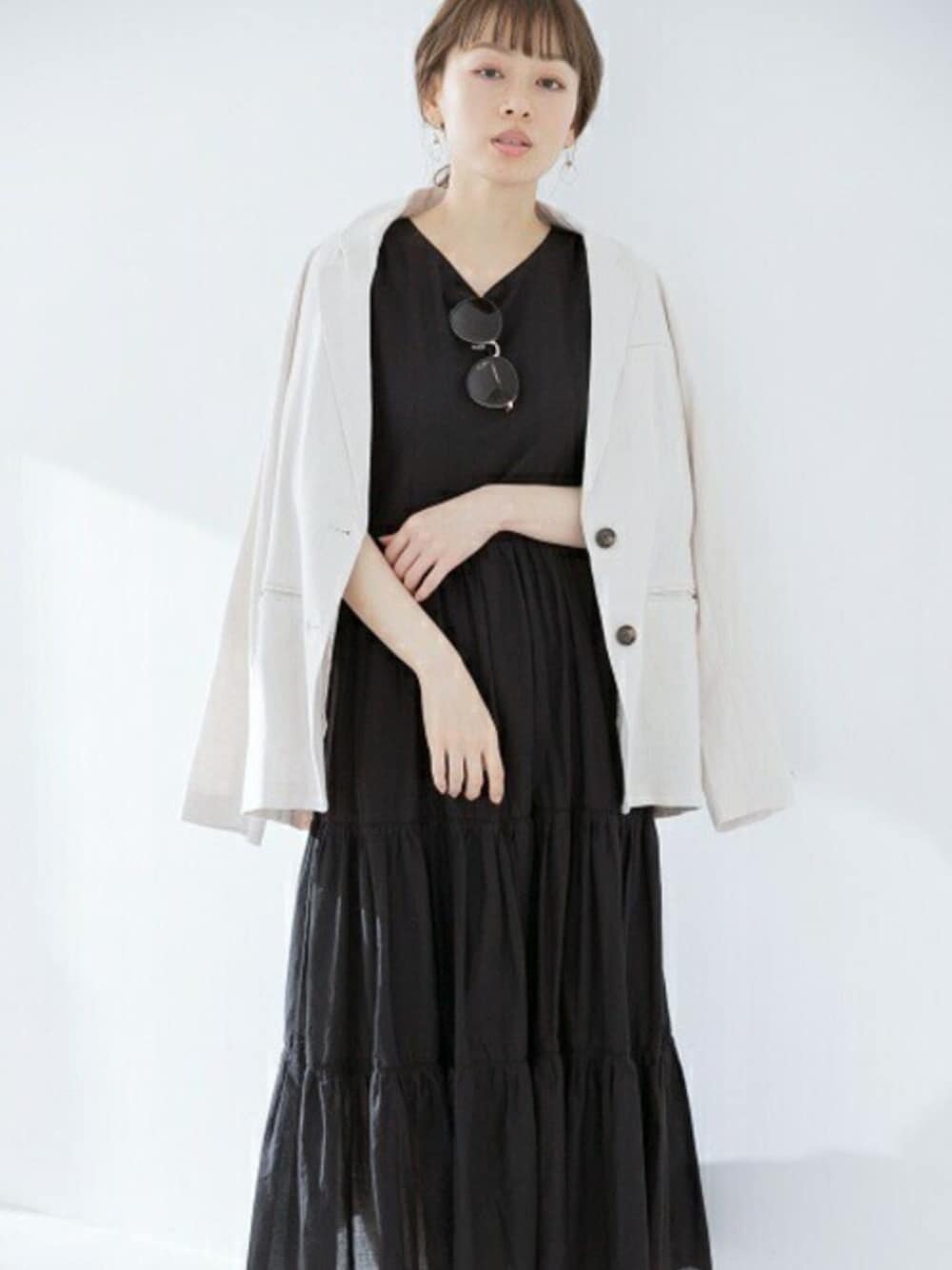 ブラック系のワンピース、ホワイト系のテーラードジャケットを着用したレディースの春コーディネートの1枚目の写真