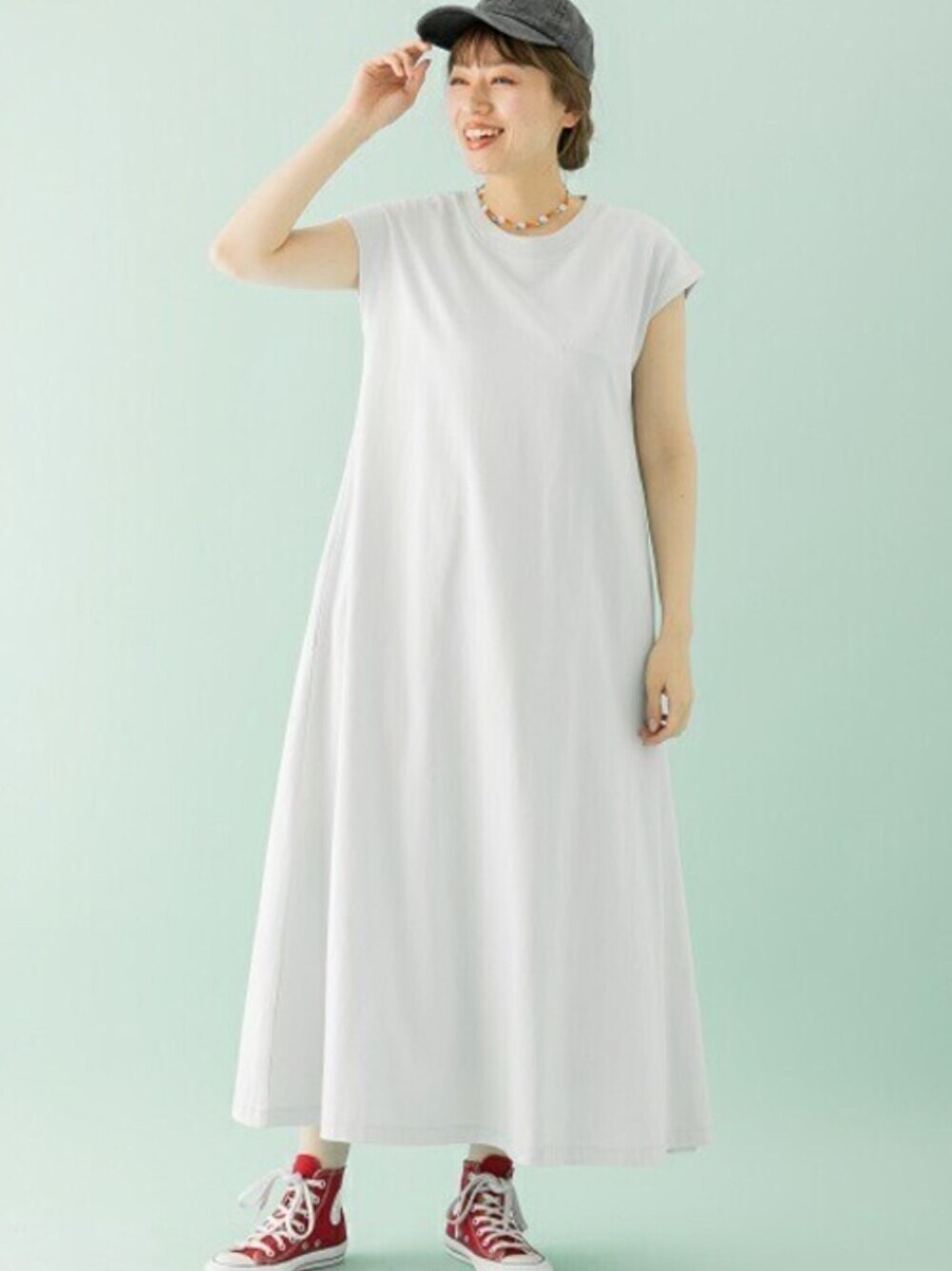 グレー系のワンピース、レッド系のスニーカー、その他のネックレスを着用したレディースの春コーディネートの1枚目の写真