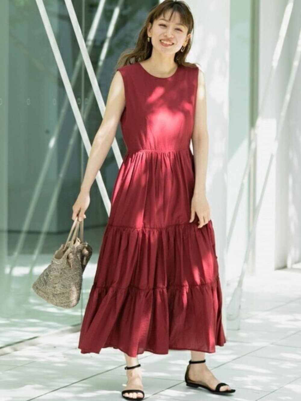 レッド系のワンピース、ブラック系のサンダル、ブラウン系のハンドバッグを着用したレディースの春コーディネートの1枚目の写真