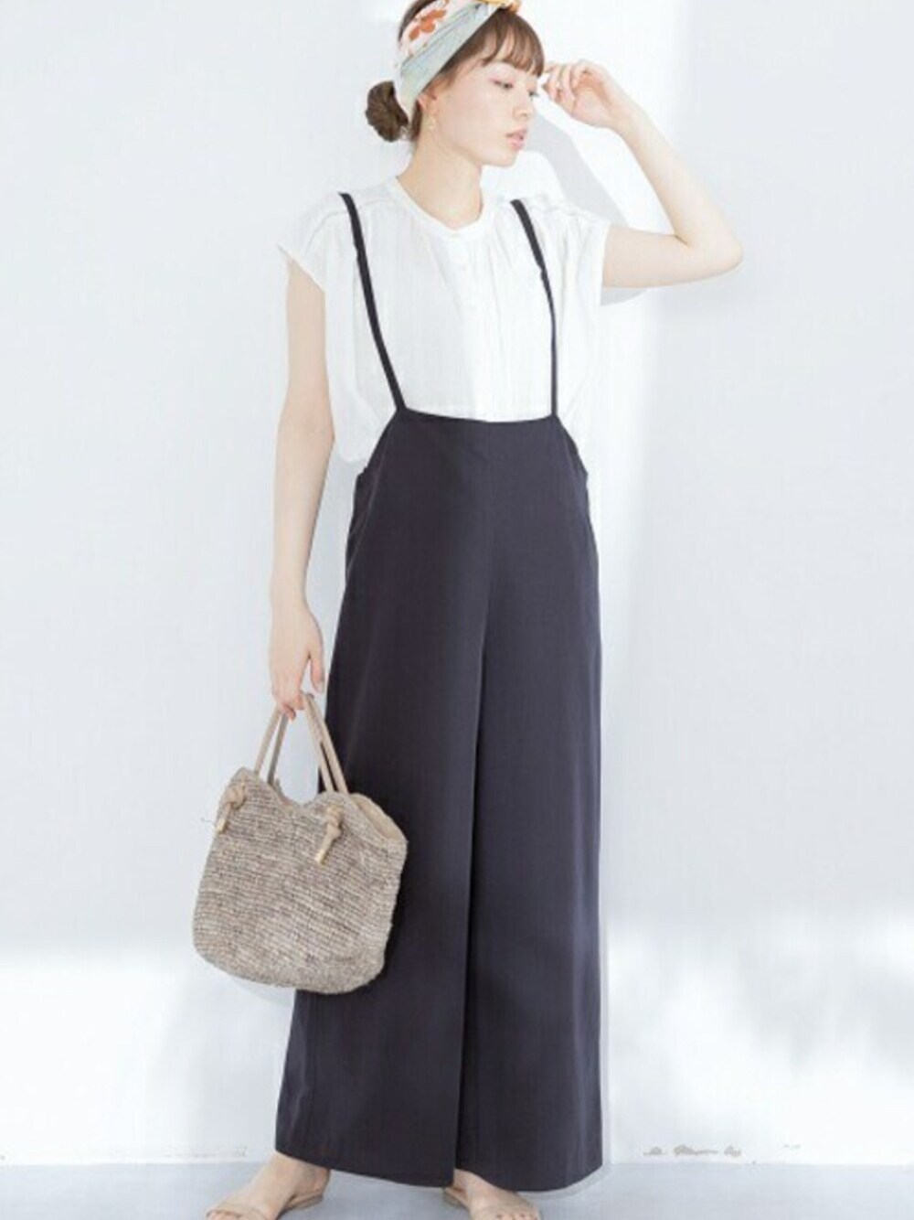 ブルー系のサロペット/オーバーオール、ホワイト系のシャツ/ブラウス、ブラウン系のハンドバッグを着用したレディースの春コーディネートの1枚目の写真