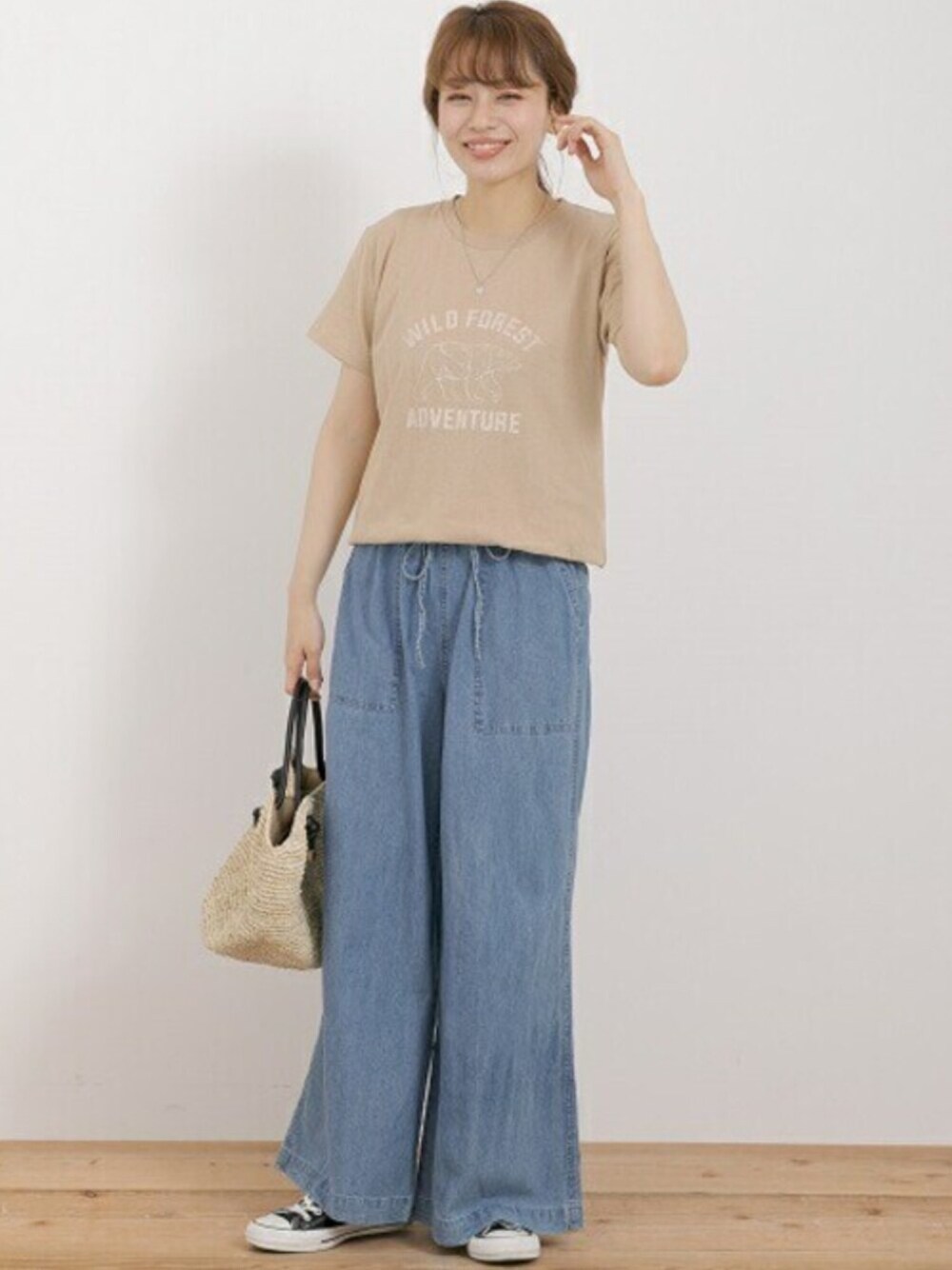 ベージュ系のTシャツ/カットソー、ブルー系のデニムパンツ、ベージュ系のハンドバッグを着用したレディースの夏コーディネートの1枚目の写真