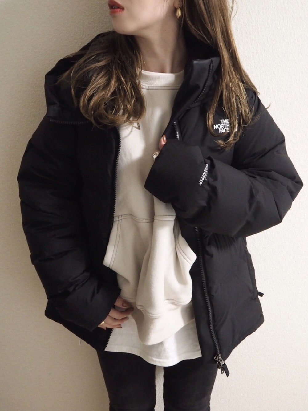 ホワイト系のスウェット、ホワイト系のTシャツ/カットソー、ブラック系のダウンジャケット/コートを着用したレディースの冬コーディネートの1枚目の写真