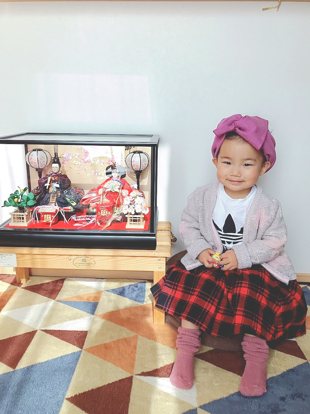 レッド系のスカート、ピンク系のカーディガン/ボレロ、ホワイト系のロンパースを着用したキッズの春コーディネートの1枚目の写真