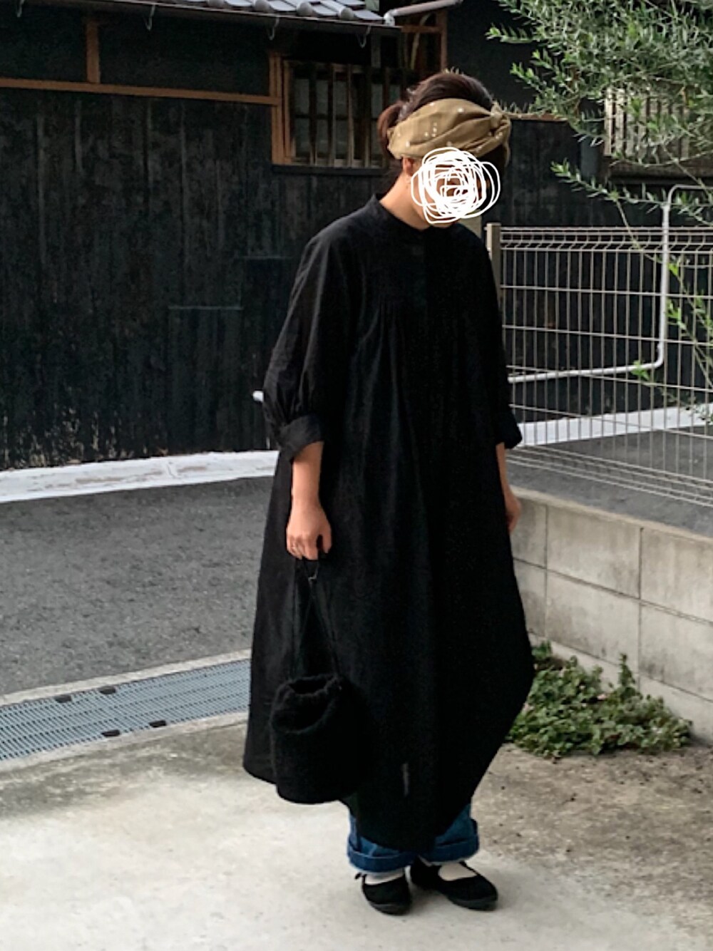 ブラック系のワンピース、ブルー系のデニムパンツ、ブラック系のバレエシューズを着用したレディースの秋コーディネートの1枚目の写真