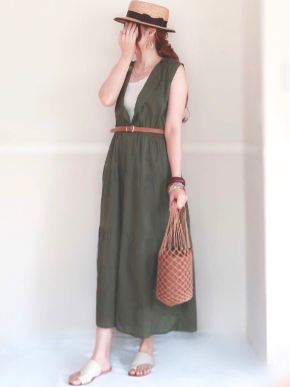 グリーン系のワンピース、ホワイト系のサンダル、ブラウン系のハンドバッグを着用したレディースの夏コーディネートの1枚目の写真