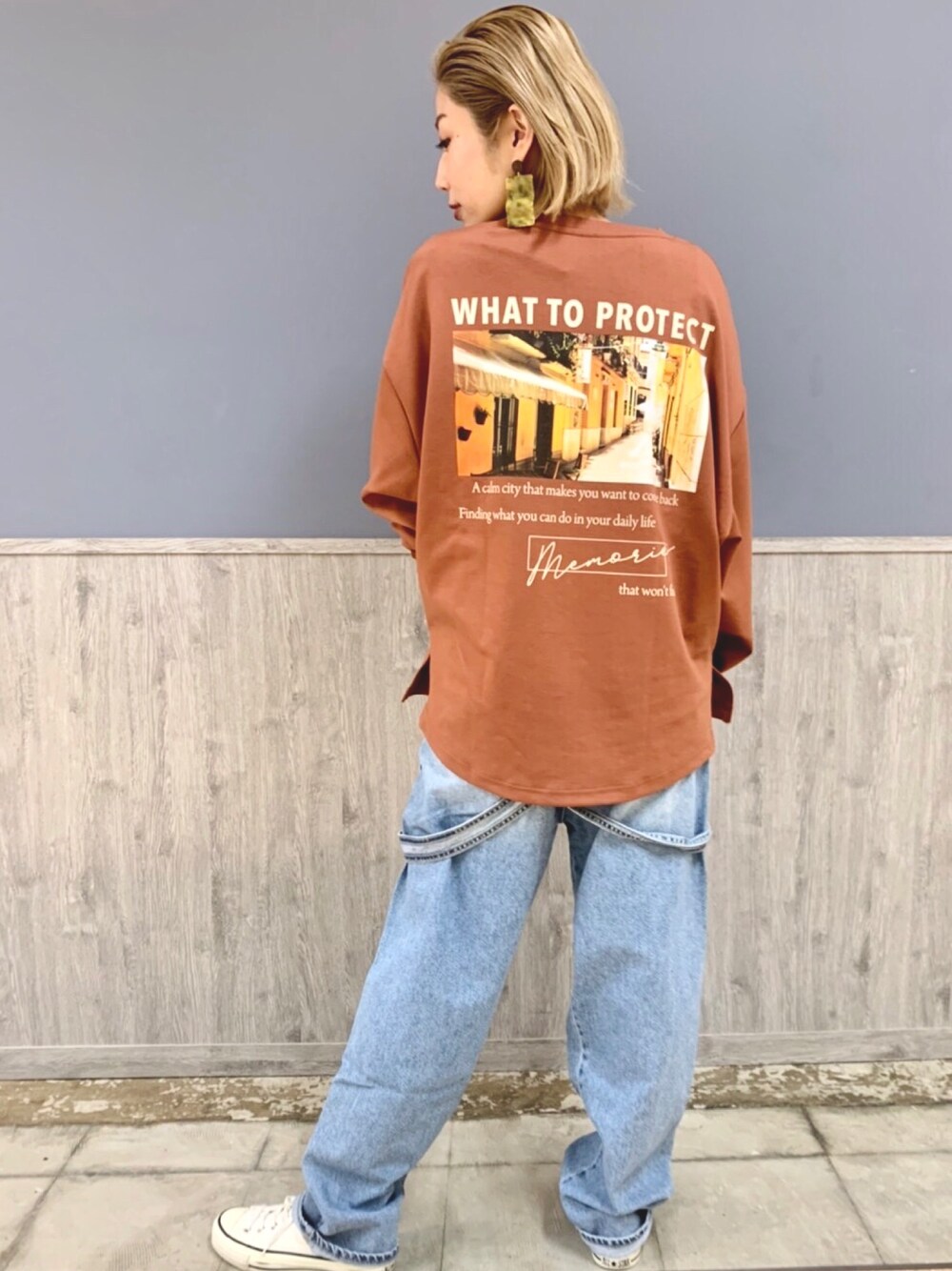 オレンジ系のトップス、ブルー系のオールインワン・サロペット、ホワイト系のスニーカーを着用したレディースの冬コーディネートの1枚目の写真