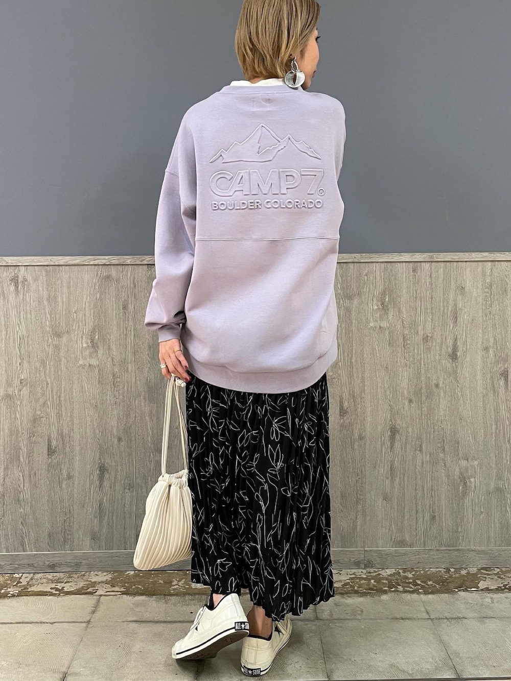 パープル系のスウェット、ブラック系のスカート、ホワイト系のショルダーバッグを着用したレディースの冬コーディネートの1枚目の写真