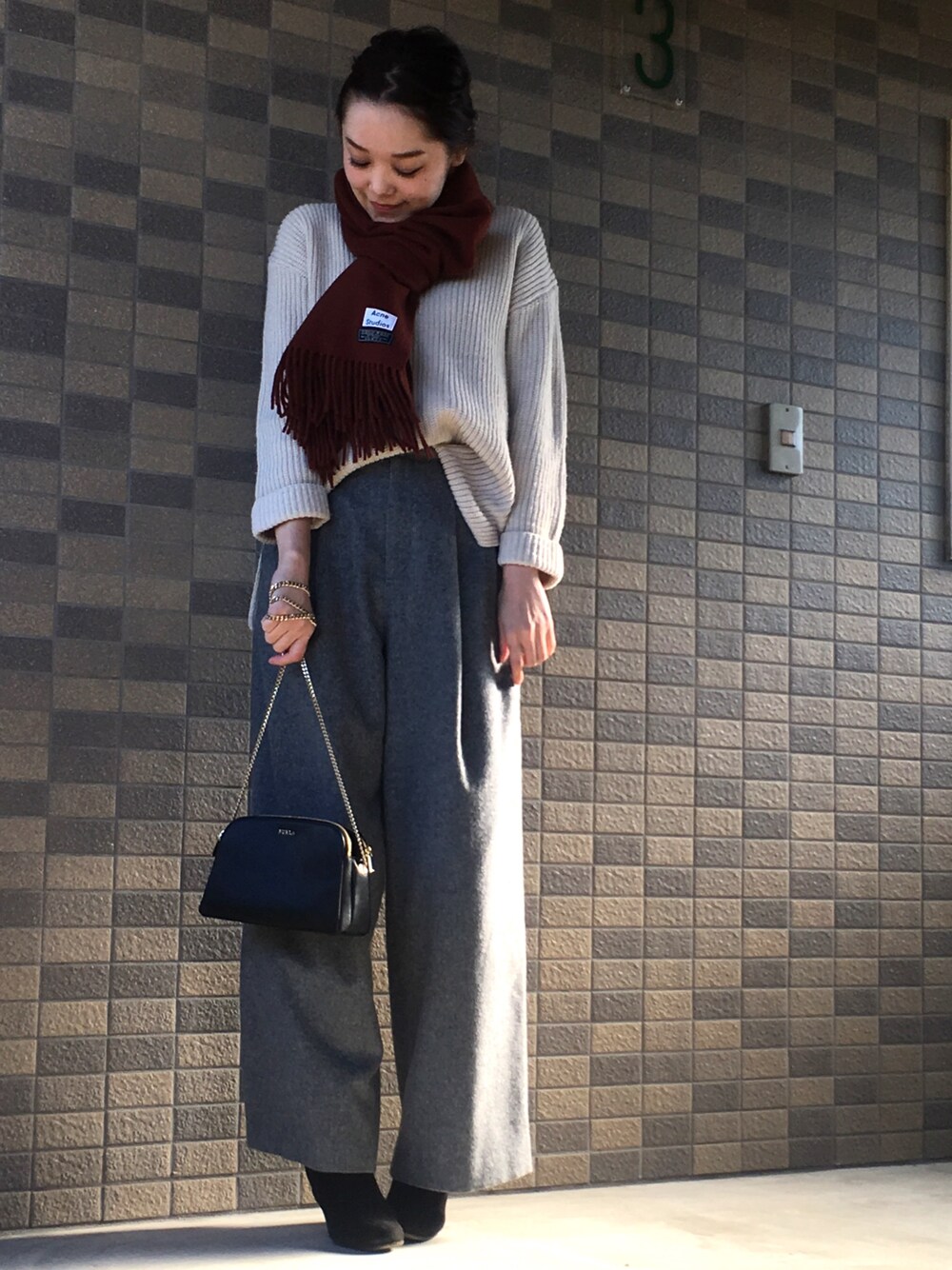 ホワイト系のニット/セーター、グレー系のその他パンツ、ブラック系のショルダーバッグを着用したレディースの冬コーディネートの1枚目の写真