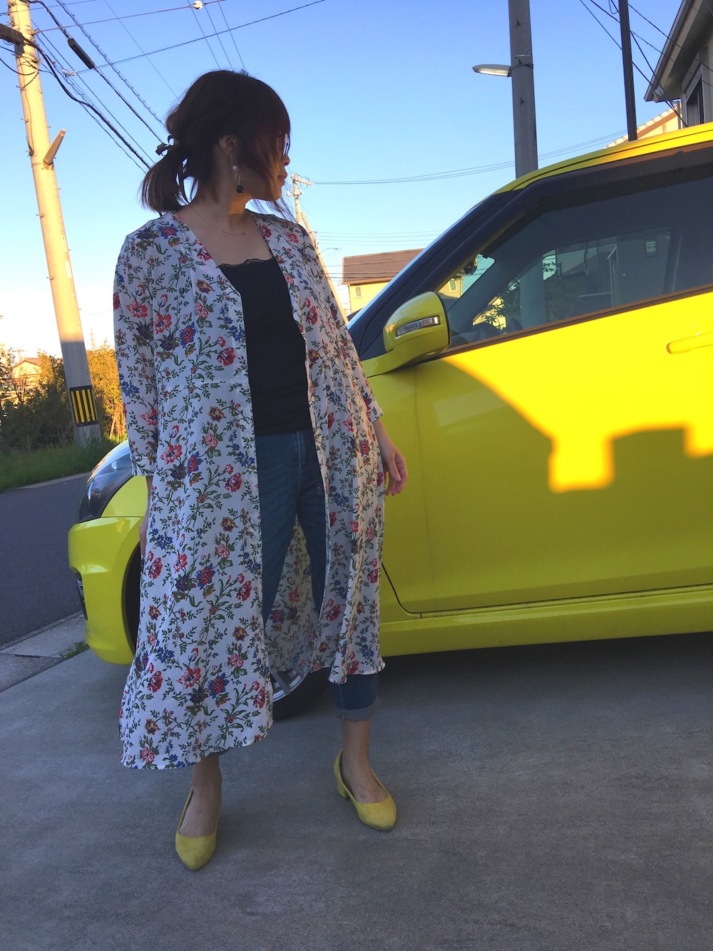 ホワイト系のシャツワンピース、ブラック系のタンクトップ、ブルー系のデニムパンツを着用したレディースの春コーディネートの1枚目の写真