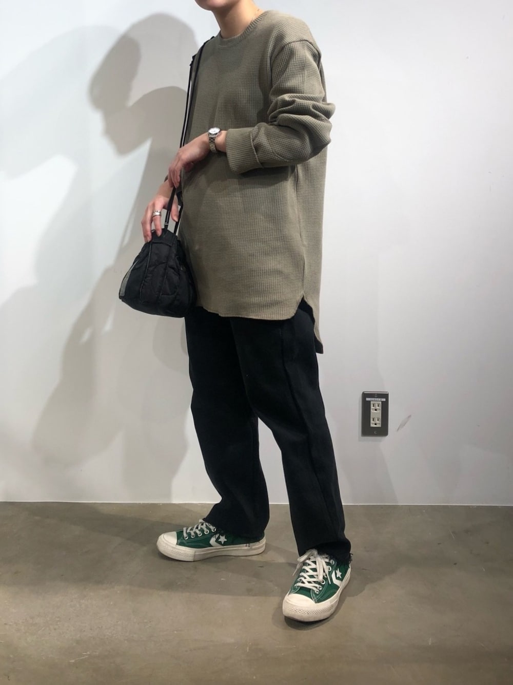 グリーン系のTシャツ/カットソー、ブラック系のデニムパンツ、ブラック系のショルダーバッグを着用したレディースの冬コーディネートの1枚目の写真