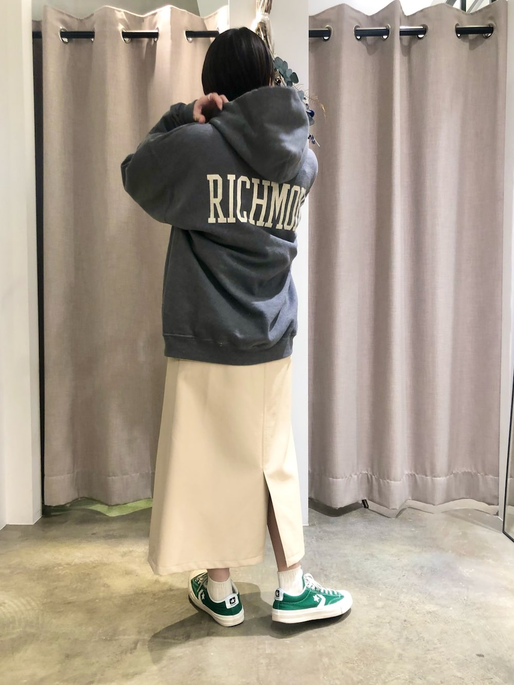 ブラック系のパーカー、ベージュ系のスカート、グリーン系のスニーカーを着用したレディースの冬コーディネートの1枚目の写真