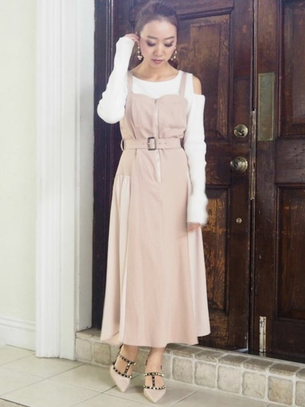 ベージュ系のジャンパースカート、ホワイト系のニット/セーター、ベージュ系のパンプスを着用したレディースの冬コーディネートの1枚目の写真