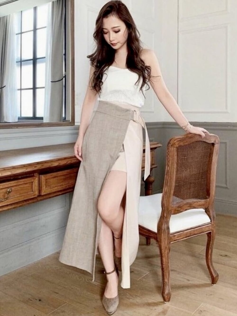 ベージュ系のスカート、ホワイト系のチューブトップ、ブラウン系のパンプスを着用したレディースの秋コーディネートの1枚目の写真