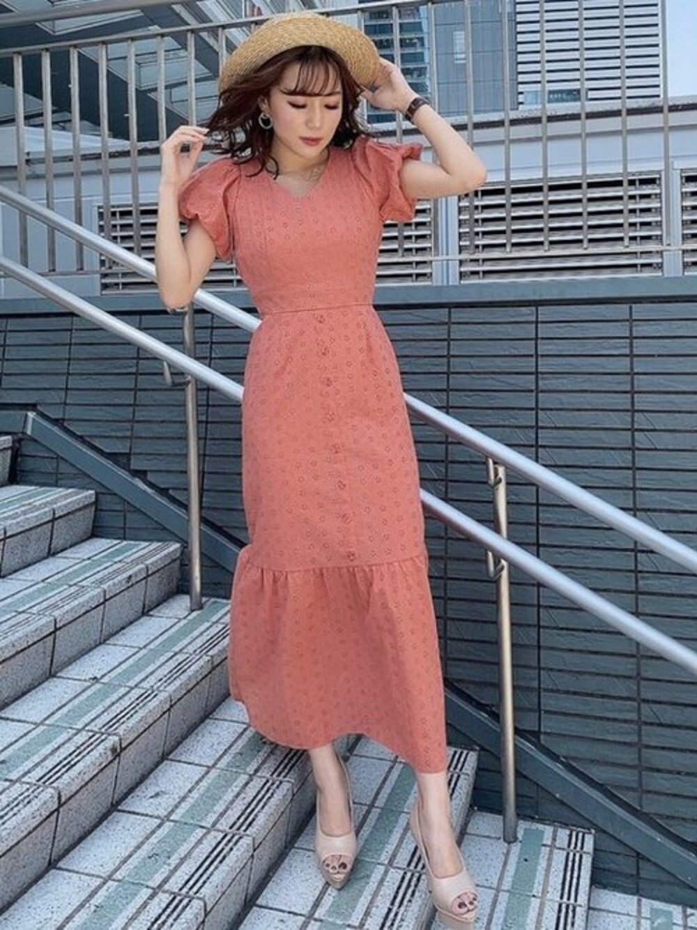 オレンジ系のワンピース、ベージュ系のパンプス、ベージュ系のハットを着用したレディースの夏コーディネートの1枚目の写真