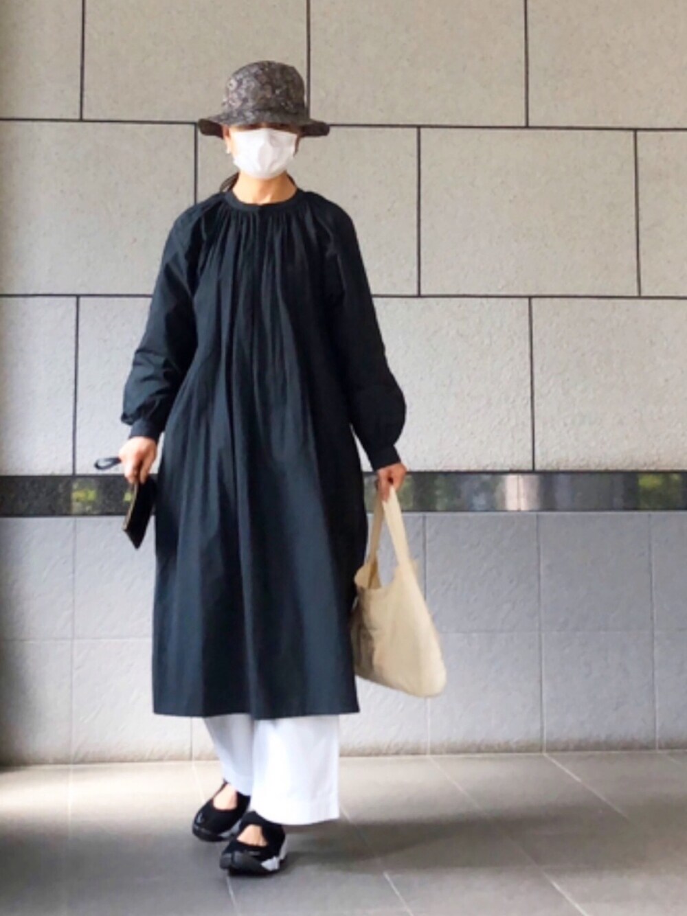 ブラック系のワンピース、ホワイト系のパンツ、ブラック系のスニーカーを着用したレディースの春コーディネートの1枚目の写真