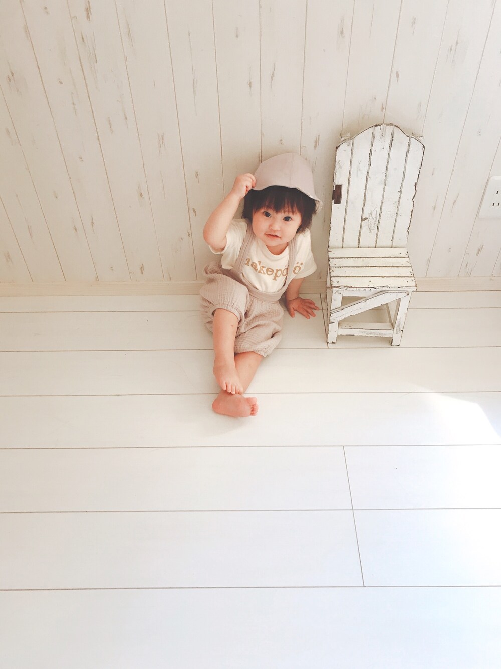 ベージュ系のオールインワン・サロペット、パープル系のハットを着用したキッズの夏コーディネートの1枚目の写真