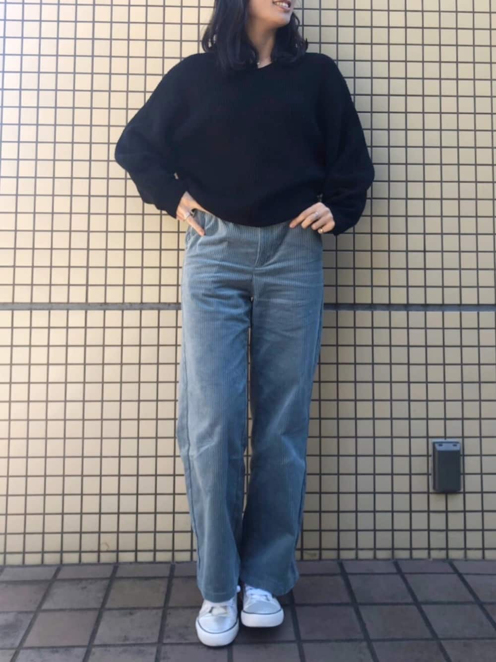 ブルー系のパンツ、シルバー系のスニーカー、ブラック系のニット/セーターを着用したレディースの秋コーディネートの1枚目の写真