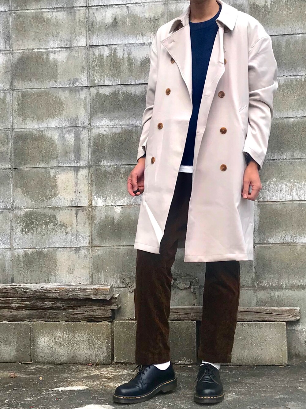 ベージュ系のトレンチコート、ブルー系のニット/セーター、ホワイト系のTシャツ/カットソーを着用したメンズの冬コーディネートの1枚目の写真