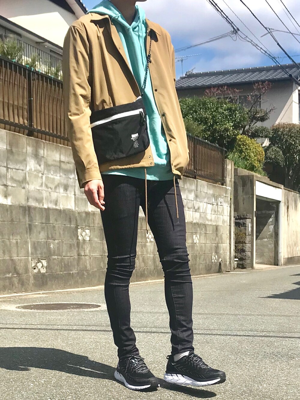 ベージュ系のその他アウター、グリーン系のパーカー、ブラック系のショルダーバッグを着用したメンズの春コーディネートの1枚目の写真