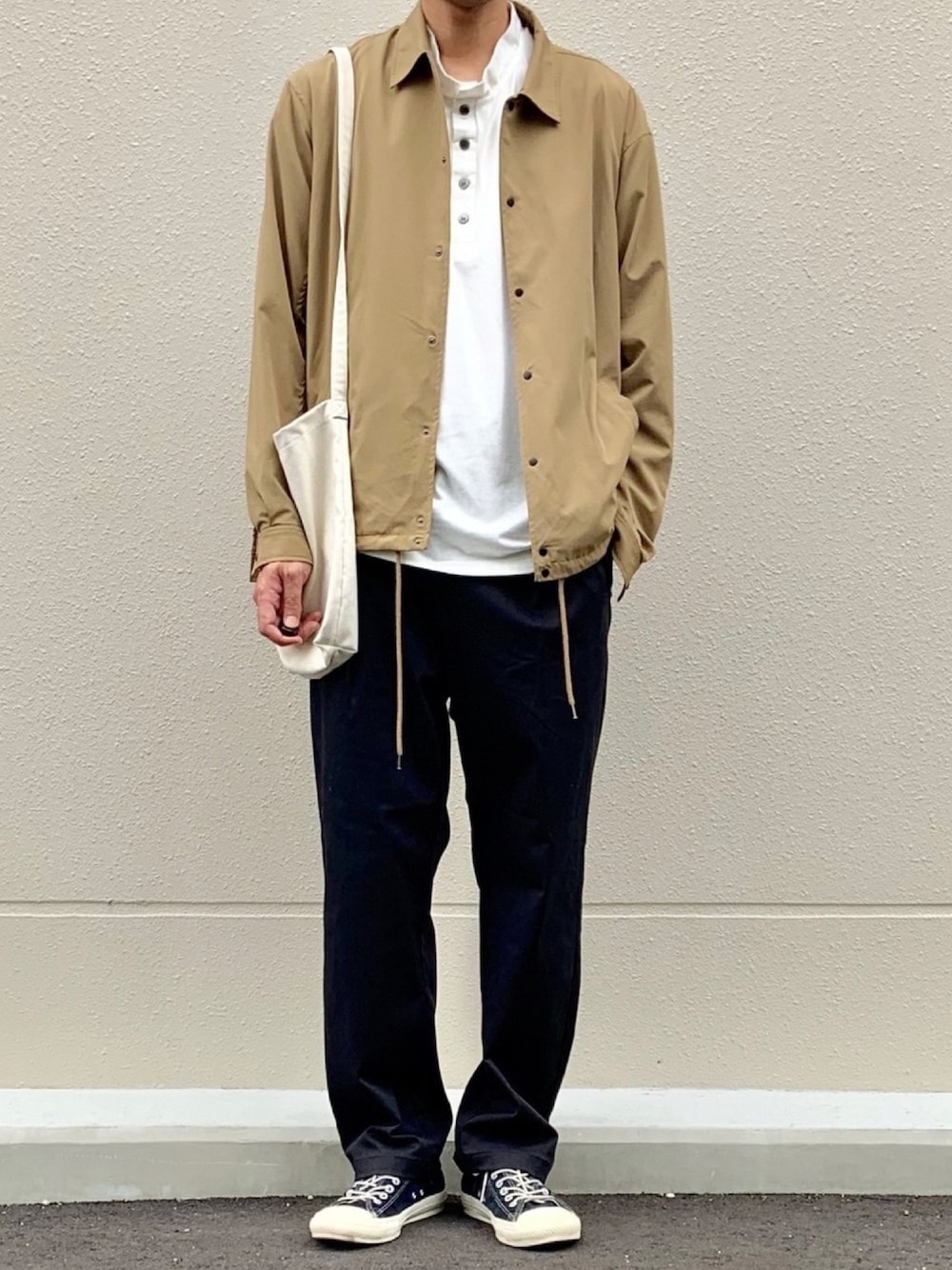 ベージュ系のその他アウター、ホワイト系のTシャツ/カットソー、ホワイト系のトートバッグを着用したメンズの秋コーディネートの1枚目の写真