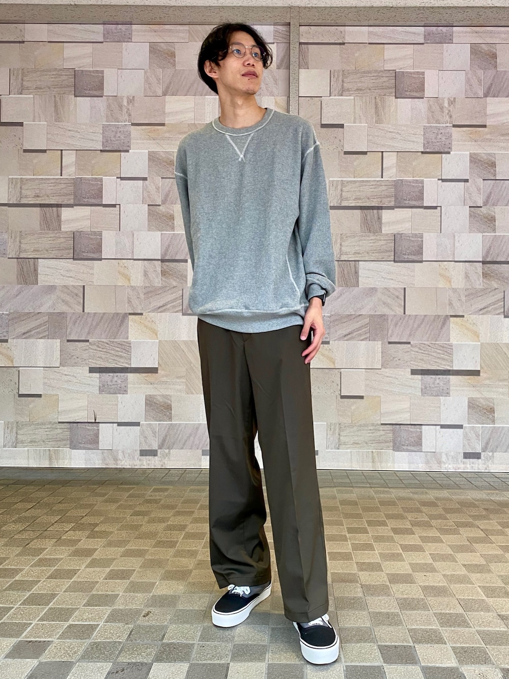 グレー系のスウェット、グリーン系のチノパンツ、ブラック系のスニーカーを着用したメンズの秋コーディネートの1枚目の写真