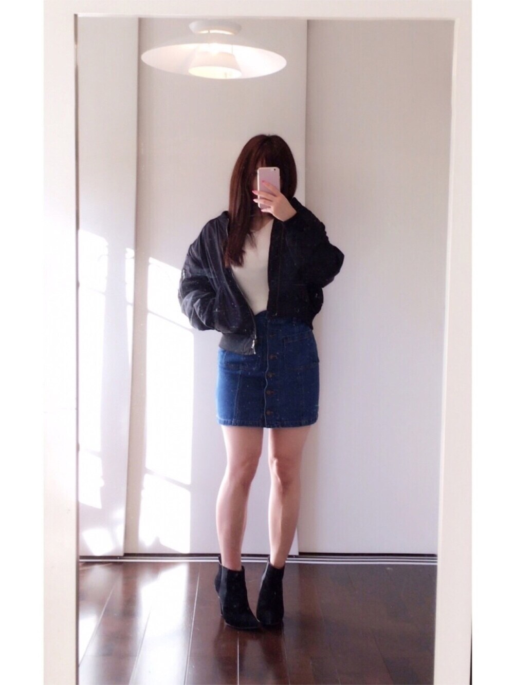 ブラック系のMA-1、ブルー系のデニムスカート、ホワイト系のニット/セーターを着用したレディースの冬コーディネートの1枚目の写真