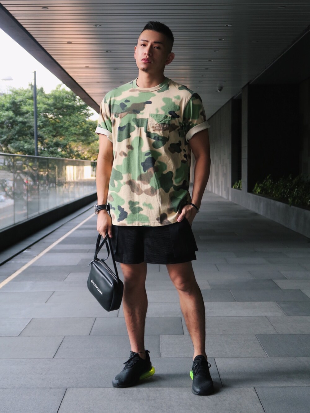 グリーン系のTシャツ/カットソー、ブラック系のショルダーバッグ、ブラック系のスニーカーを着用したメンズの春コーディネートの1枚目の写真