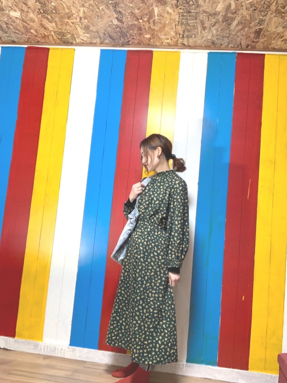 グリーン系のワンピース、ブルー系のトートバッグ、ブルー系のデニムパンツを着用したレディースの冬コーディネートの1枚目の写真