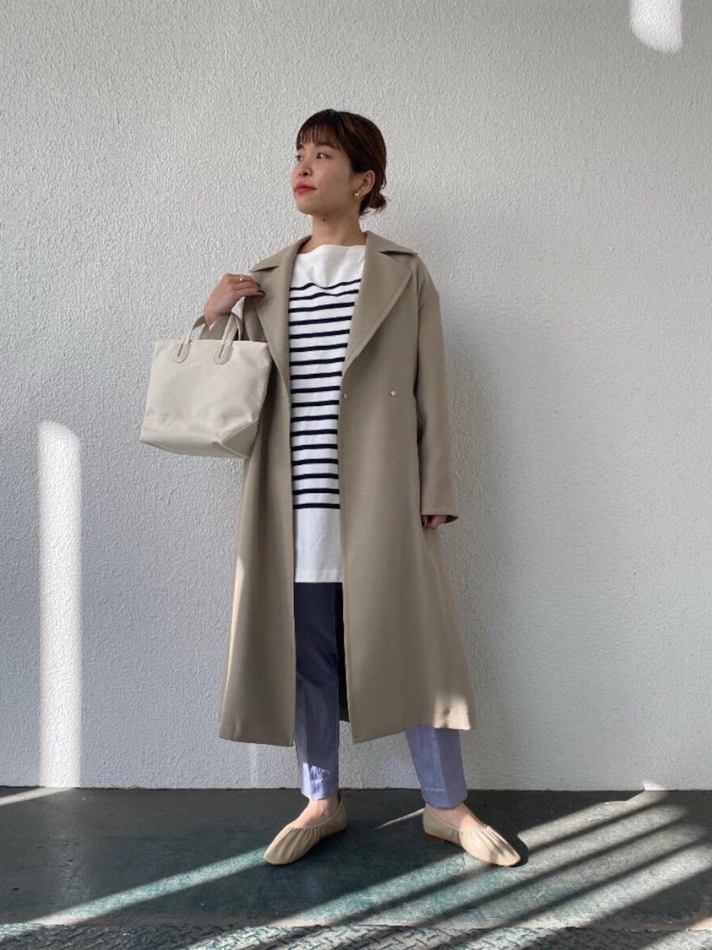ブルー系のTシャツ/カットソー、ベージュ系のトレンチコート、ベージュ系のバレエシューズを着用したレディースの冬コーディネートの1枚目の写真