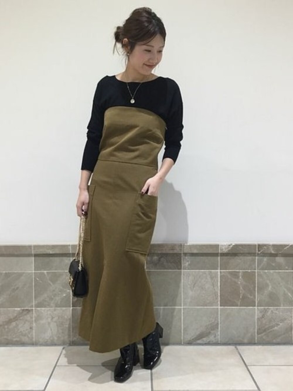 グリーン系のワンピース、ブラック系のニット/セーター、その他のショルダーバッグを着用したレディースの冬コーディネートの1枚目の写真