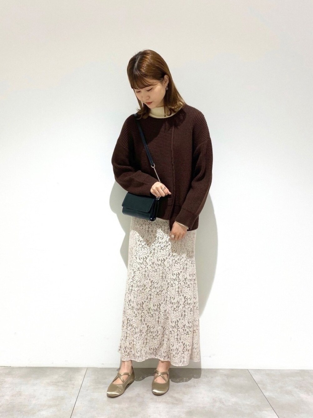 ホワイト系のTシャツ/カットソー、ブラウン系のニット/セーター、ブラック系のショルダーバッグを着用したレディースの秋コーディネートの1枚目の写真