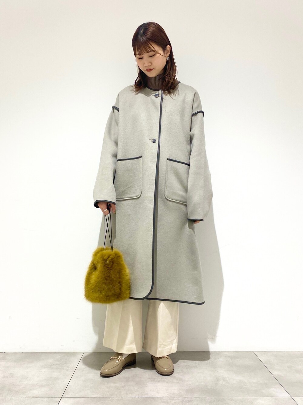 グリーン系のノーカラージャケット、ブラウン系のニット/セーター、ホワイト系のその他パンツを着用したレディースの冬コーディネートの1枚目の写真