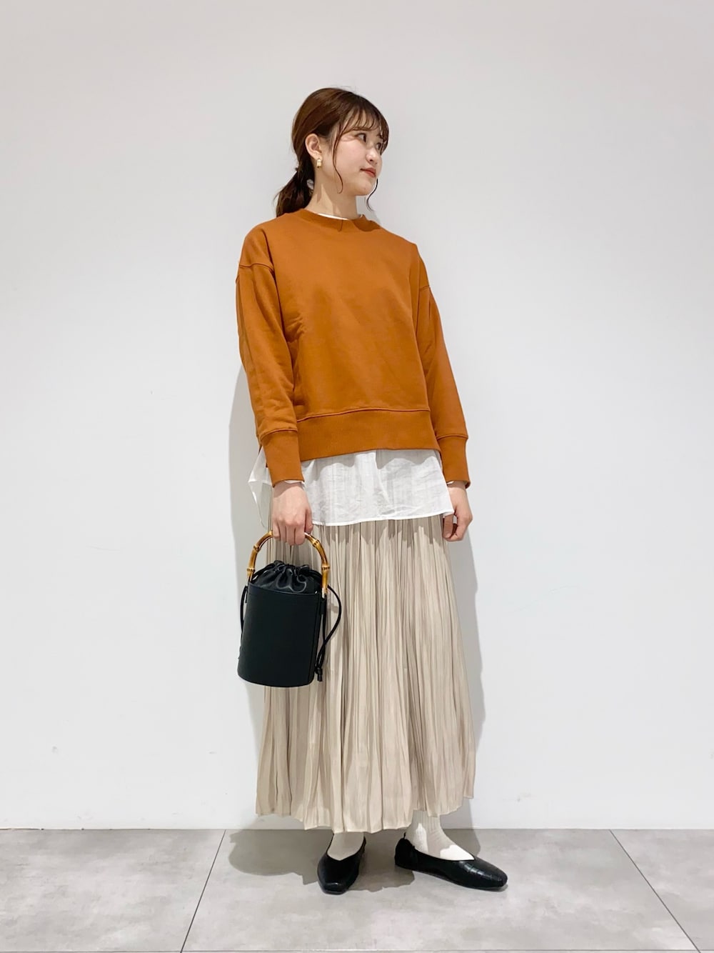 オレンジ系のスウェット、ホワイト系のシャツ/ブラウス、ブラック系のショルダーバッグを着用したレディースの冬コーディネートの1枚目の写真