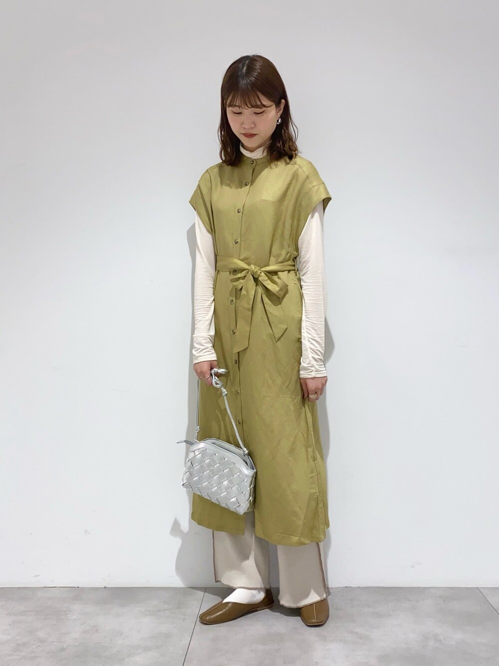 シルバー系のショルダーバッグ、イエロー系のワンピース、ホワイト系のTシャツ/カットソーを着用したレディースの春コーディネートの1枚目の写真