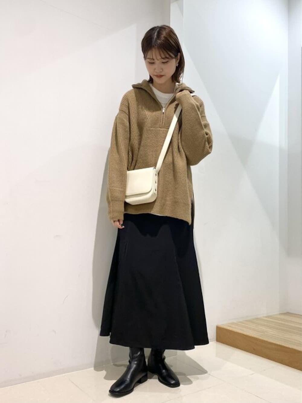 ホワイト系のTシャツ/カットソー、ベージュ系のニット/セーター、ブラック系のスカートを着用したレディースの冬コーディネートの1枚目の写真