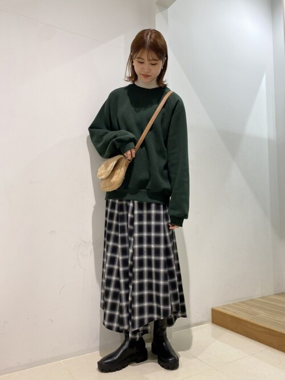 ブラック系のブーツ、グリーン系のスウェット、ホワイト系のニット/セーターを着用したレディースの冬コーディネートの1枚目の写真