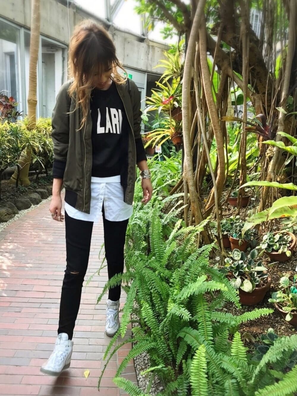 グリーン系のミリタリージャケット、ブラック系のトップス、ホワイト系のワンピースを着用したレディースの春コーディネートの1枚目の写真