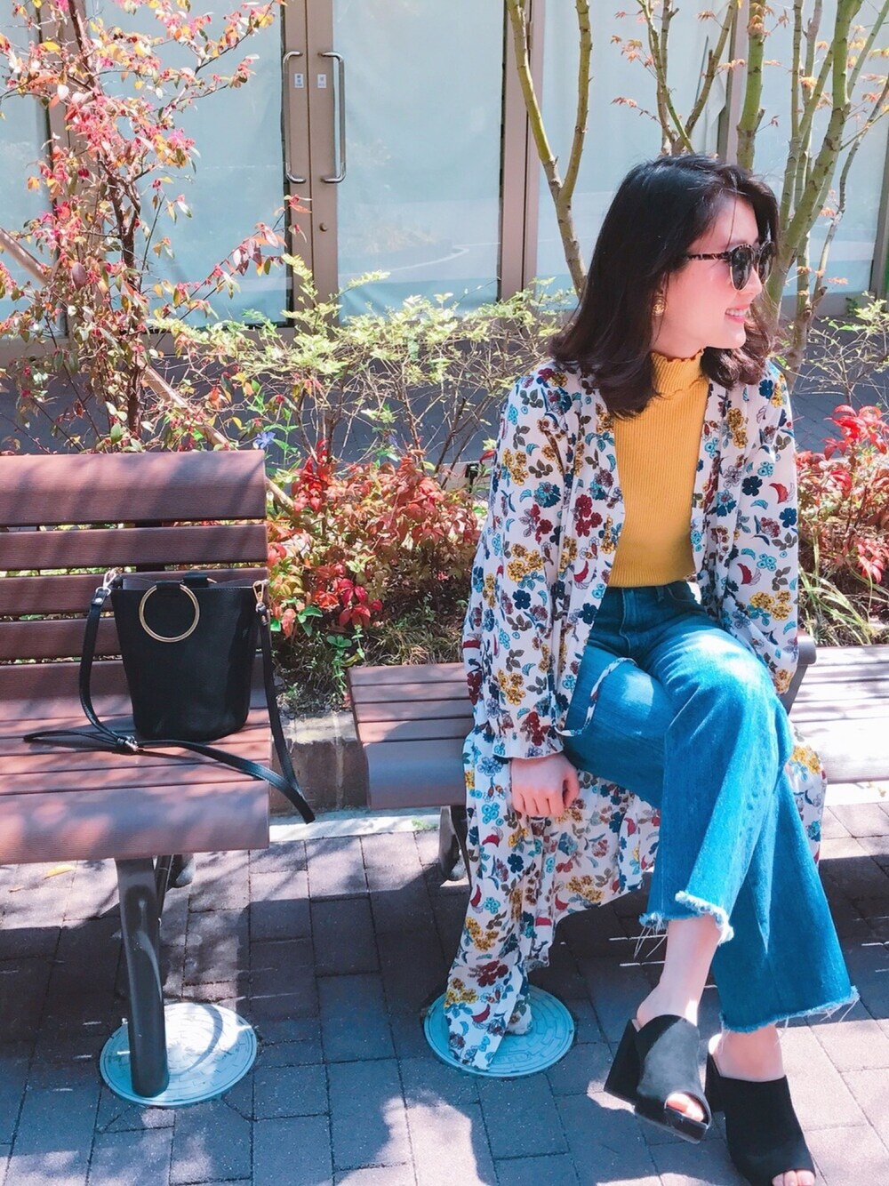 ブルー系のデニムパンツ、イエロー系のニット/セーター、ブラック系のサンダルを着用したレディースの春コーディネートの1枚目の写真